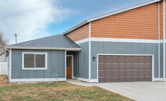 view of front of home featuring a front lawn, concrete driveway, a garage, a shingled roof, and board and batten siding