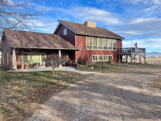 view of front of property with a patio area, a front lawn, and a deck with mountain view