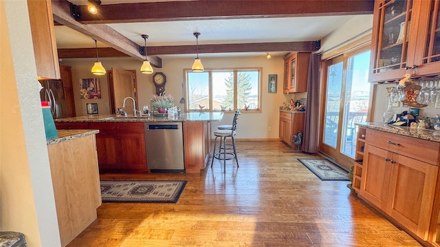 kitchen with stainless steel dishwasher, a kitchen bar, decorative light fixtures, and sink