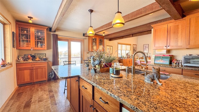 kitchen with beamed ceiling, plenty of natural light, dark hardwood / wood-style floors, and hanging light fixtures