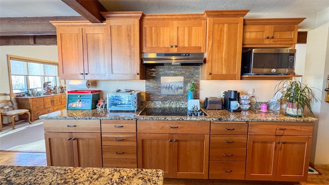 6809 N Montana Ave, Helena, MT 59602 - kitchen with stainless steel microwave, stone counters, beam ceiling, under cabinet range hood, and black electric cooktop