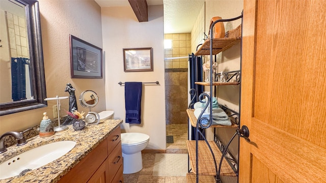 bathroom featuring a tile shower, vanity, a textured ceiling, and toilet