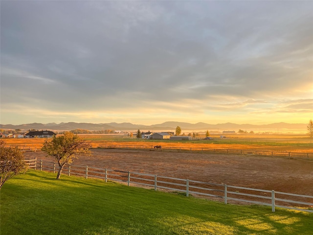 yard at dusk featuring a rural view and a mountain view