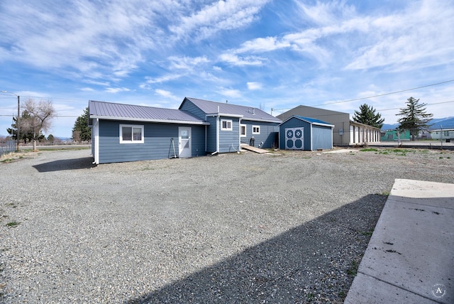single story home featuring driveway, an outbuilding, metal roof, and a shed