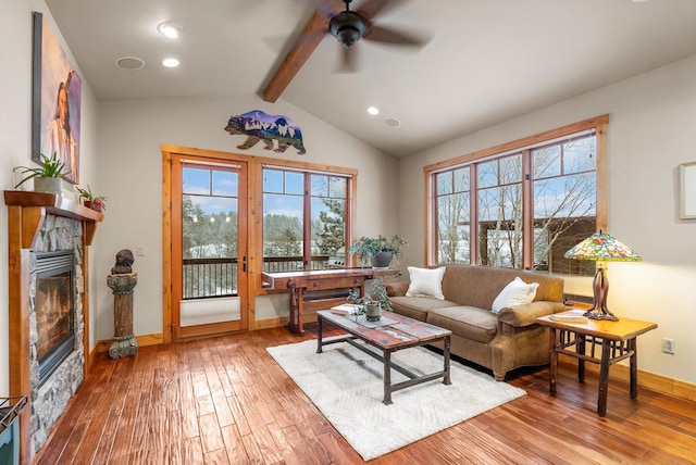 living area featuring light wood-style floors, plenty of natural light, a fireplace, and vaulted ceiling with beams