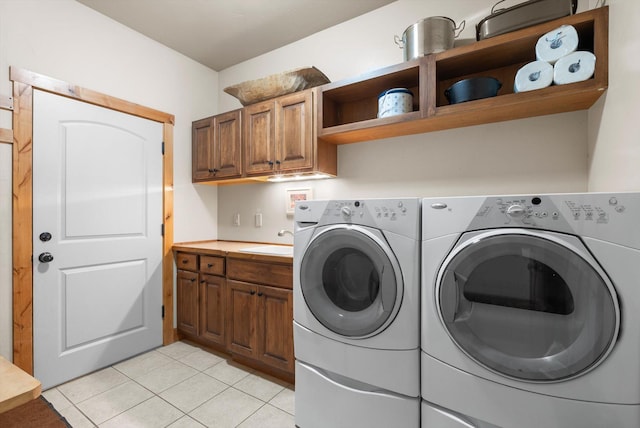 laundry room featuring cabinet space, light tile patterned flooring, a sink, and independent washer and dryer