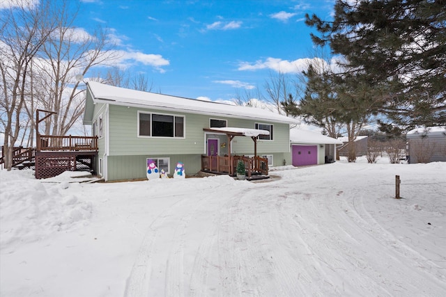 snow covered house featuring a garage and a wooden deck