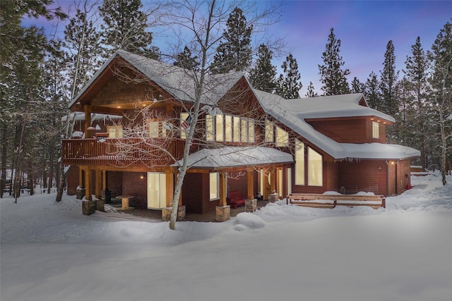 snow covered back of property with a wooden deck