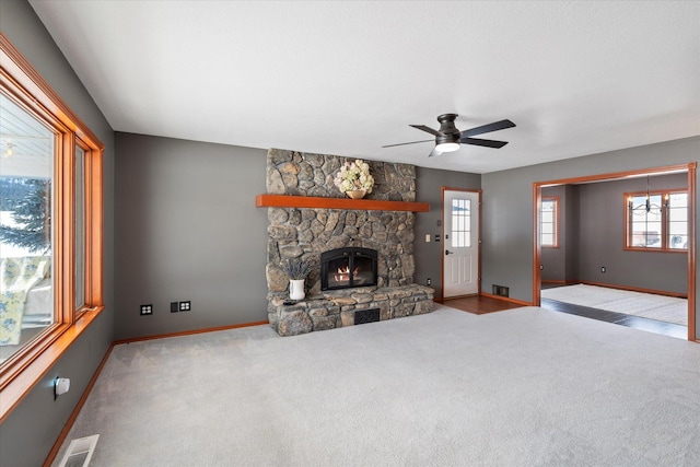carpeted living area with baseboards, a fireplace, visible vents, and a ceiling fan
