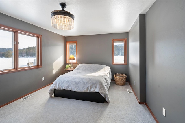 carpeted bedroom with baseboards, visible vents, and a notable chandelier