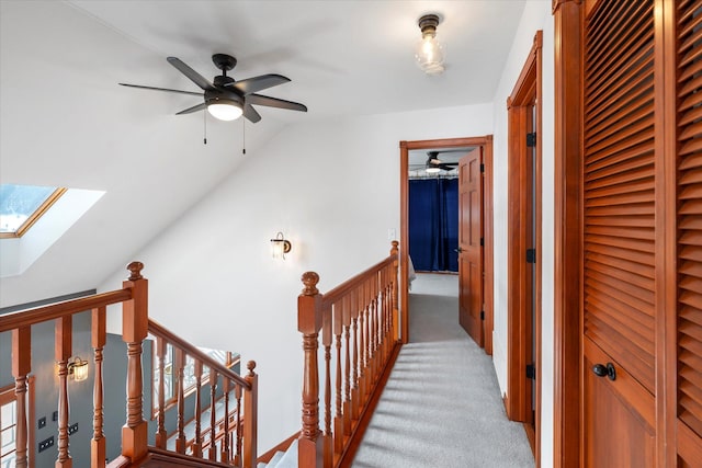 corridor featuring light carpet, an upstairs landing, and lofted ceiling with skylight