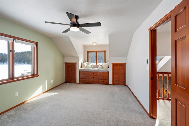 bonus room with a textured ceiling, lofted ceiling, baseboards, light colored carpet, and ceiling fan