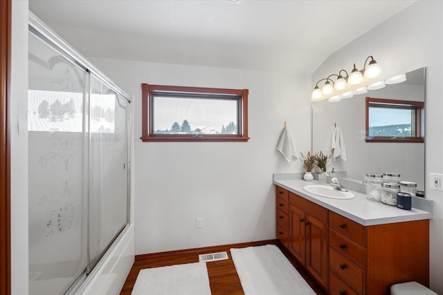 full bathroom featuring visible vents, baseboards, wood finished floors, vanity, and enclosed tub / shower combo