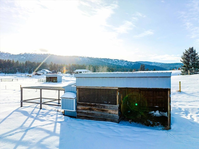 snow covered structure featuring an outdoor structure and a mountain view