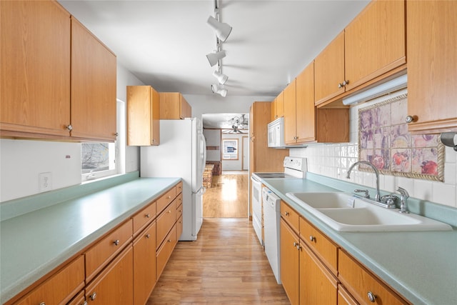 kitchen with white appliances, a sink, light countertops, light wood-type flooring, and backsplash