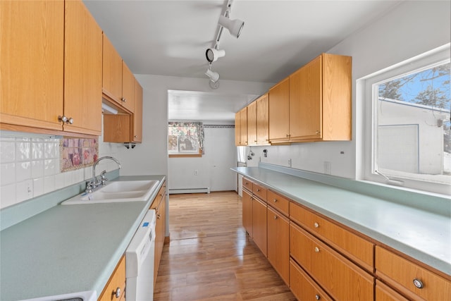 kitchen featuring decorative backsplash, dishwasher, light countertops, light wood-type flooring, and a sink