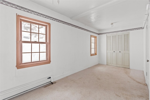 unfurnished bedroom with a baseboard heating unit, a closet, and carpet