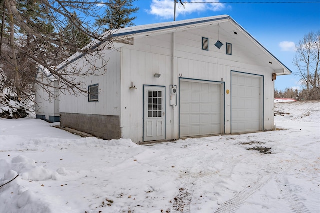 snow covered garage featuring a garage