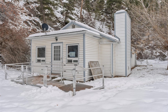 snow covered rear of property featuring a chimney