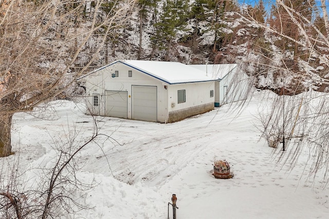 snow covered structure featuring a garage