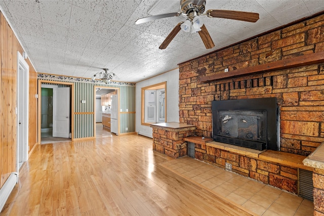 unfurnished living room featuring baseboards, a fireplace, a ceiling fan, and light wood-style floors