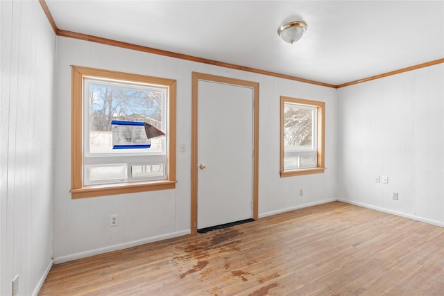 spare room with light wood-style flooring, crown molding, baseboards, and a wealth of natural light