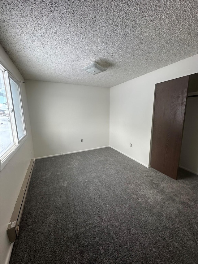 605 Idaho St, Deer Lodge, MT 59722 - unfurnished bedroom featuring dark carpet, a textured ceiling, and baseboards