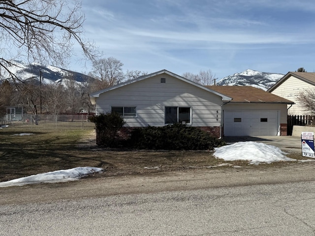 view of property exterior featuring a mountain view, an attached garage, fence, and brick siding