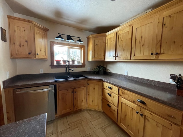 kitchen featuring dark countertops, dishwasher, a textured ceiling, and a sink