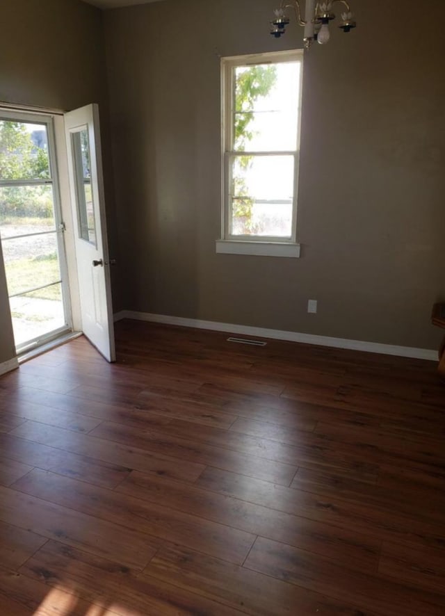 200 Cleveland Rd, Chinook, MT 59523 - unfurnished room with a chandelier, plenty of natural light, dark wood-style floors, and baseboards