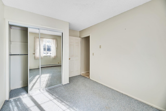 unfurnished bedroom with a closet, carpet flooring, a textured ceiling, and a baseboard heating unit