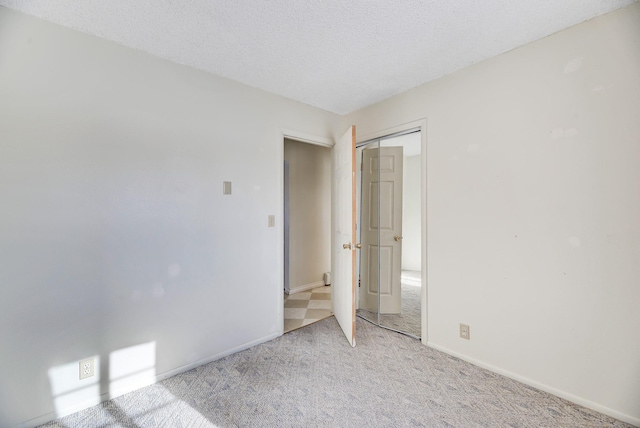 unfurnished bedroom featuring light carpet, a closet, and a textured ceiling