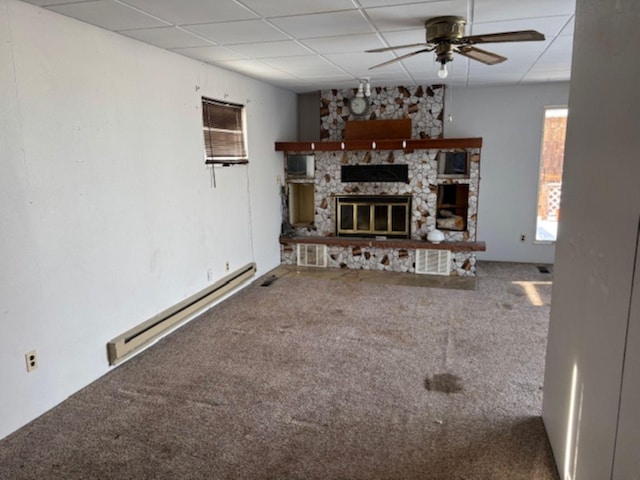 unfurnished living room with a baseboard heating unit, ceiling fan, a fireplace, carpet, and a drop ceiling