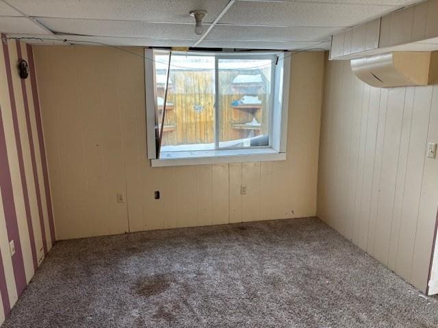 unfurnished room with carpet floors and wood walls