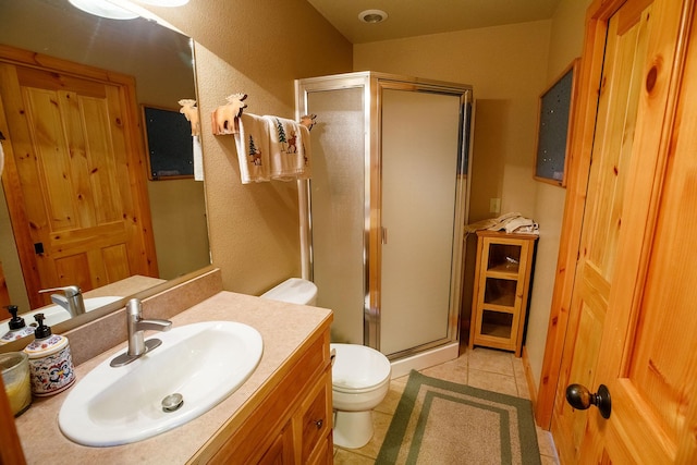 bathroom featuring a shower with door, vanity, tile patterned flooring, and toilet