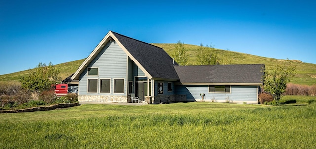 rear view of property featuring a mountain view and a lawn