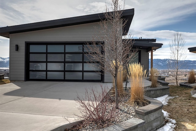 view of property exterior with a garage, concrete driveway, and a mountain view