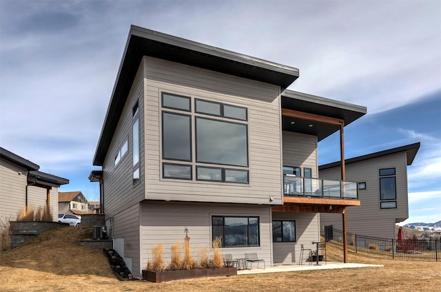 rear view of house featuring a patio area, fence, a balcony, and central air condition unit