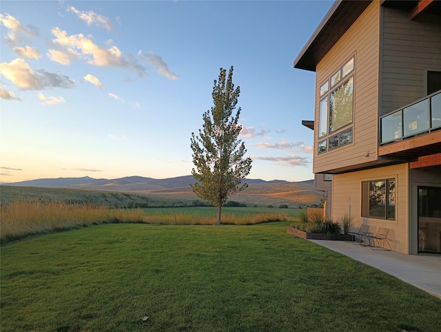 yard at dusk with a patio and a mountain view