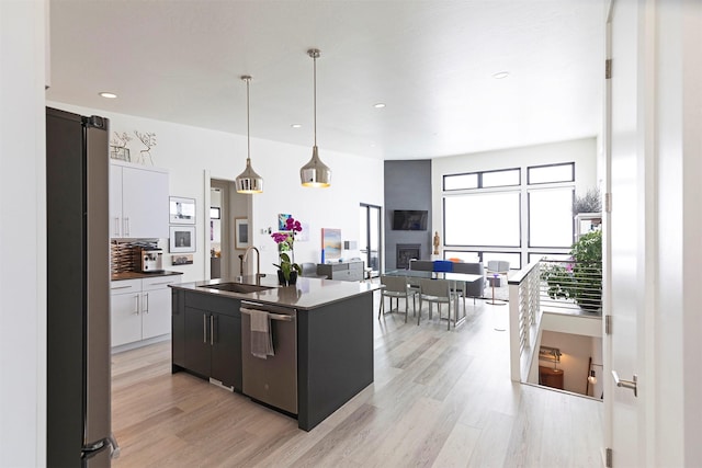 kitchen featuring sink, white cabinetry, pendant lighting, stainless steel appliances, and an island with sink