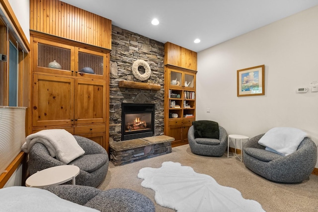 carpeted living room featuring a stone fireplace