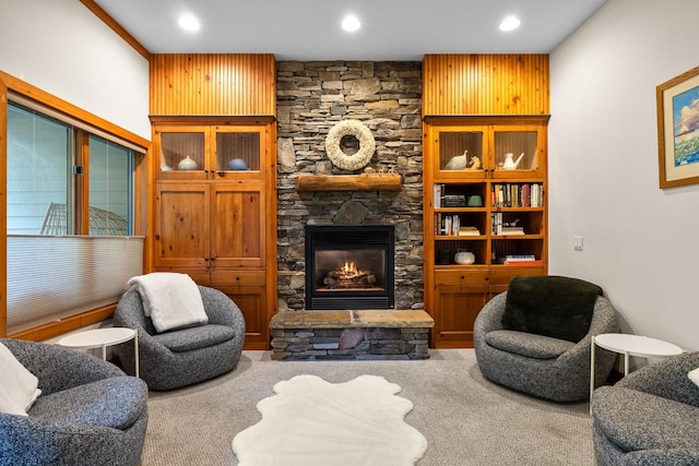 carpeted living room with a stone fireplace