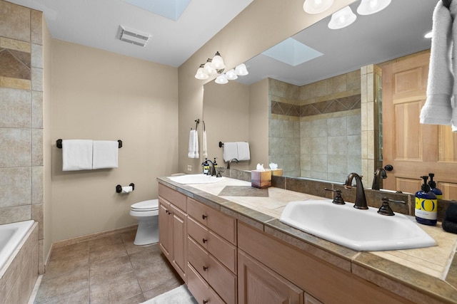 bathroom featuring toilet, tiled bath, a skylight, tile patterned floors, and vanity