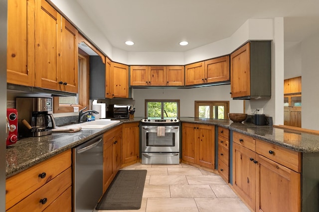 kitchen featuring dark stone countertops, sink, stainless steel appliances, and kitchen peninsula