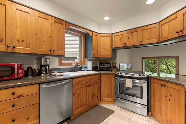 kitchen with appliances with stainless steel finishes, light tile patterned floors, sink, and a healthy amount of sunlight