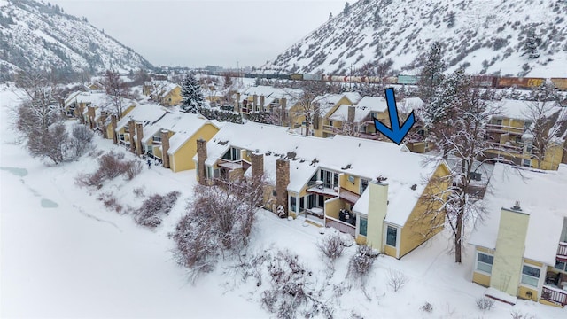 snowy aerial view featuring a residential view and a mountain view