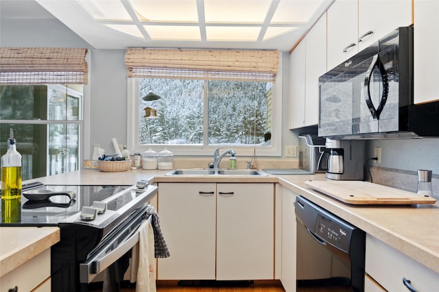 kitchen featuring light countertops, black appliances, a sink, and white cabinetry