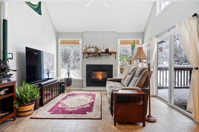 living room with high vaulted ceiling, light tile patterned flooring, and a glass covered fireplace