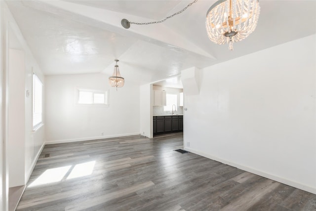 unfurnished living room featuring an inviting chandelier, dark wood-type flooring, vaulted ceiling, and sink