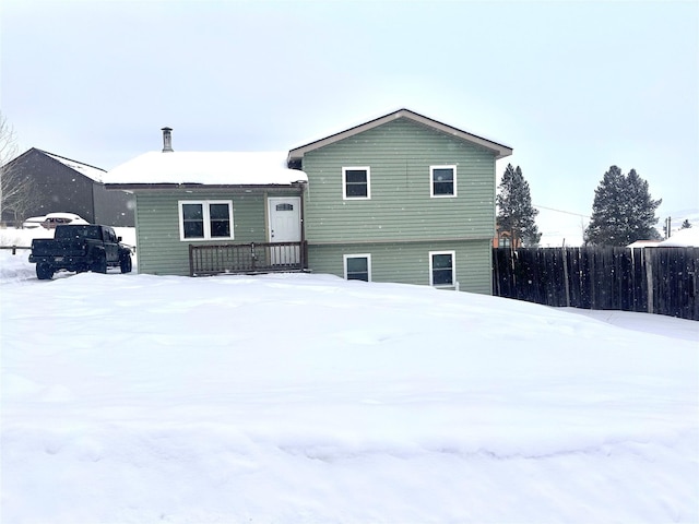 snow covered back of property with fence